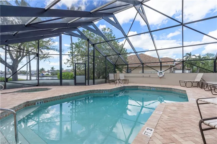 View of swimming pool with glass enclosure, a patio, and an in ground hot tub