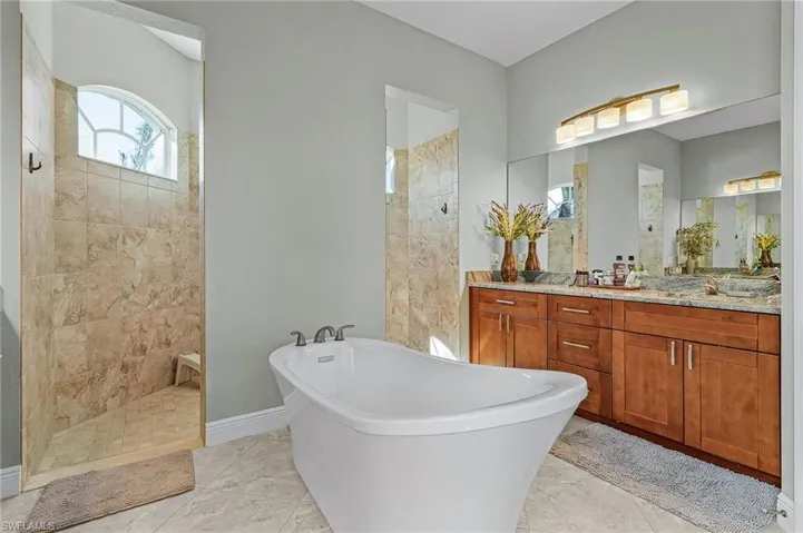 Primary Bathroom with soaking tub and counter with cherry cabinets for her, and with walk-through shower.