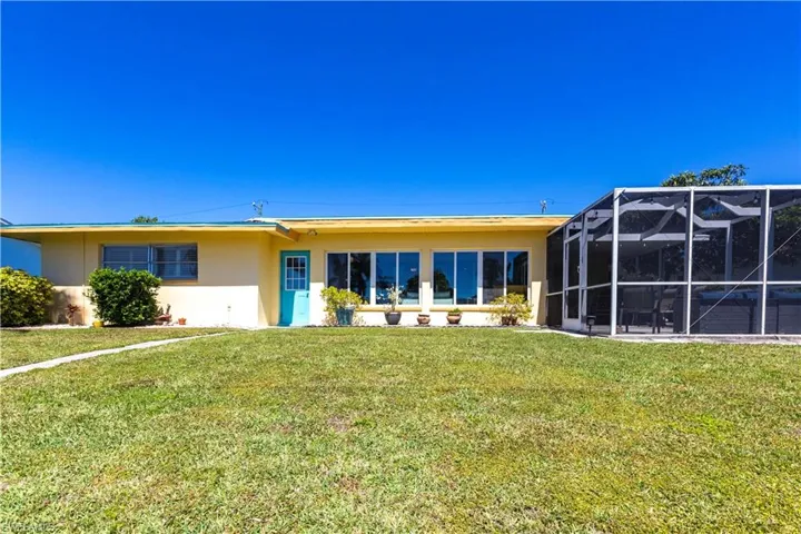 Back of house with added Screen Room, a lawn, and stucco siding. Pool?