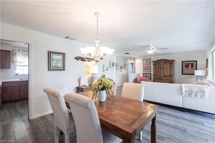 Open Dining space featuring ceiling fan with notable chandelier, wood laminated floors,
