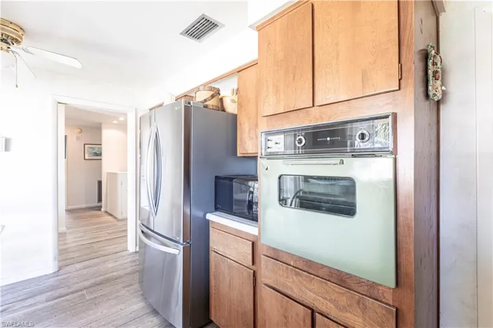 Kitchen with built in oven,  light wood-style flooring, and freestanding new French Door refrigerator