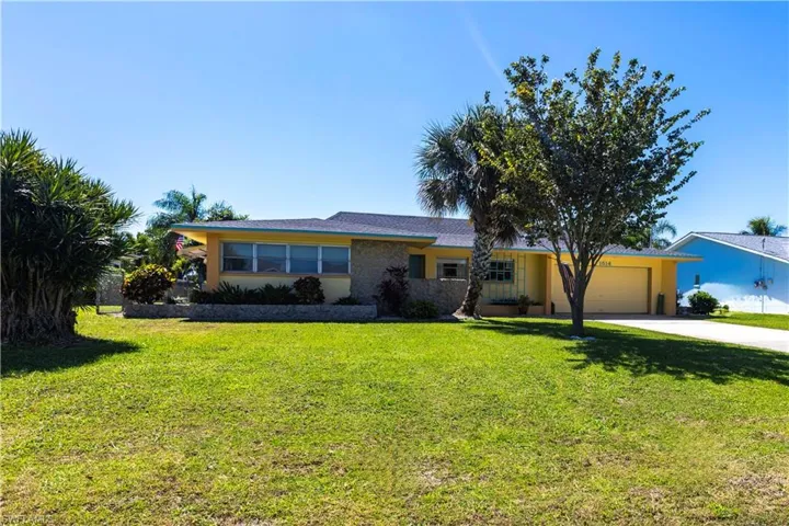 Ranch-style home with stucco siding, a landscaped front yard, concrete driveway, and an attached garage