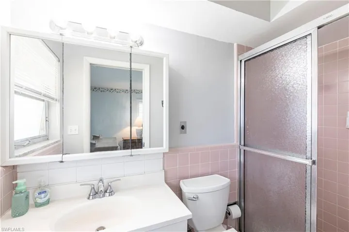 Full Main bath with vanity, triple mirrowed medicine cabinet, a walk in shower stall, tile walls, and toilet