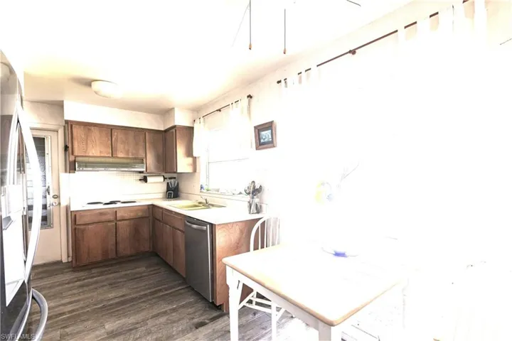 Kitchen with a sink, stainless steel appliances, light countertops,  wood-style floors, and under cabinet range hood and cook top