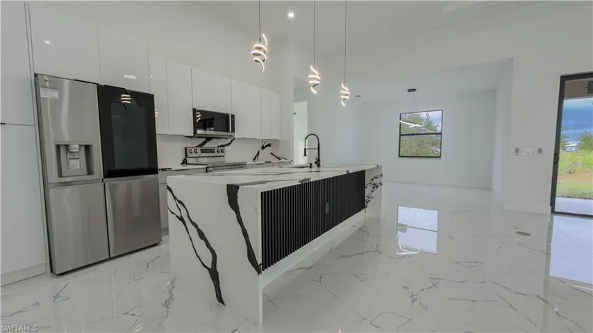 Kitchen with stainless steel appliances, decorative light fixtures, light marble finish floors, modern cabinets, and light stone countertops