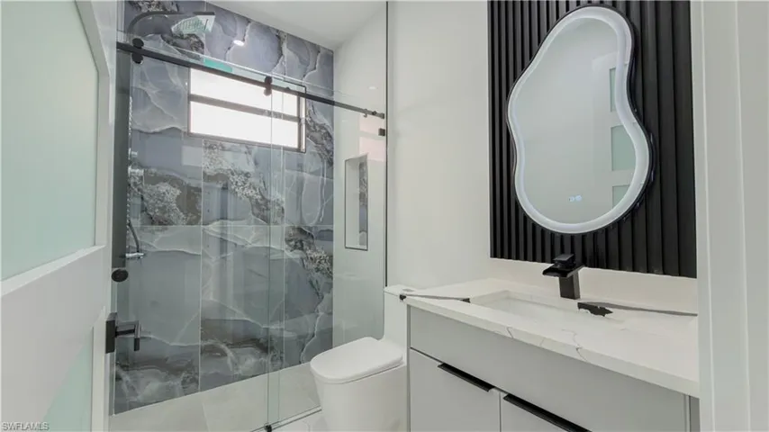 Bathroom with a marble finish shower and vanity