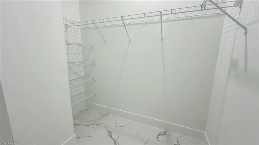 Spacious closet featuring light marble finish floors