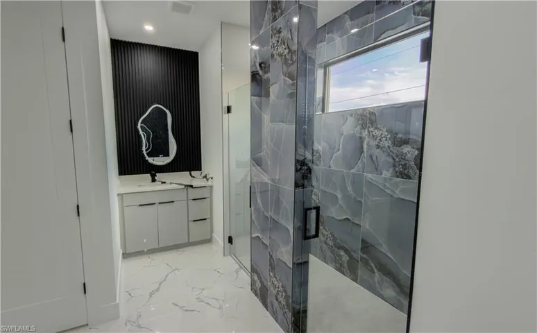 Bathroom with vanity, light marble finish flooring, a marble finish shower, and recessed lighting