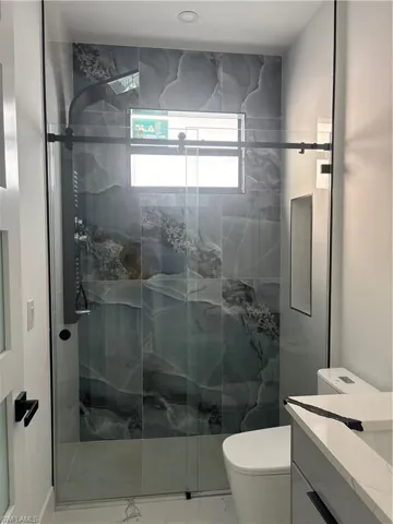 Bathroom with a marble finish shower, vanity, and marble finish flooring