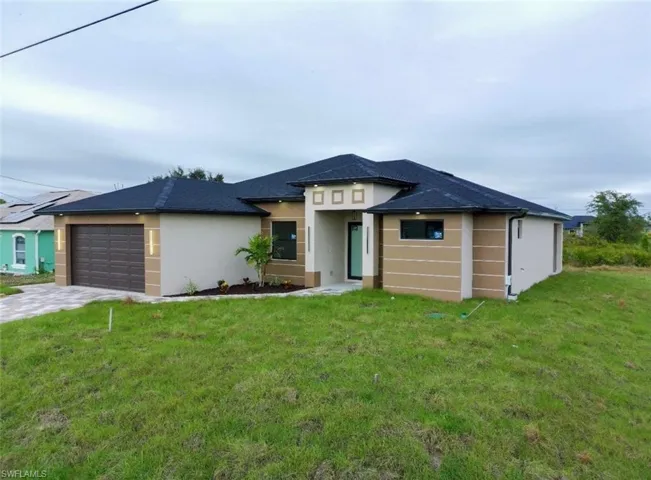 Prairie-style home with stucco siding, a front lawn, a garage, and driveway