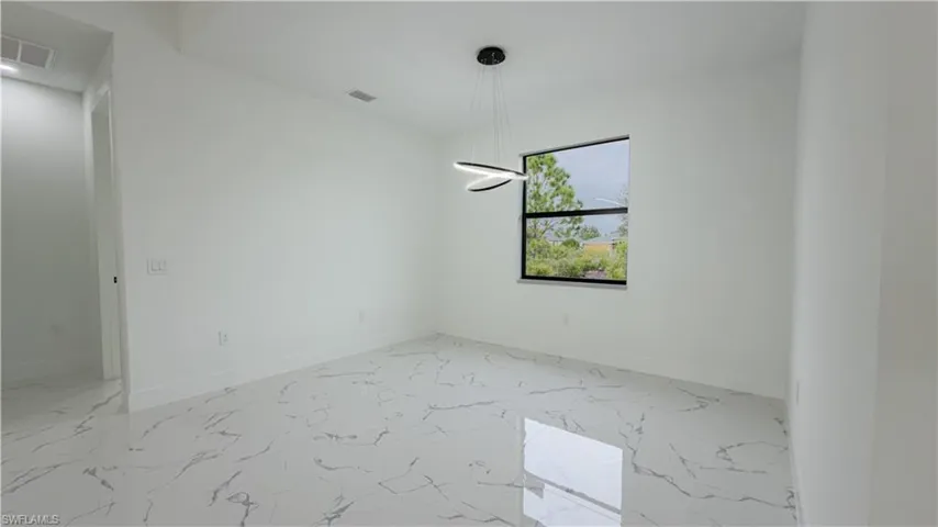 Spare room featuring light marble finish flooring and baseboards