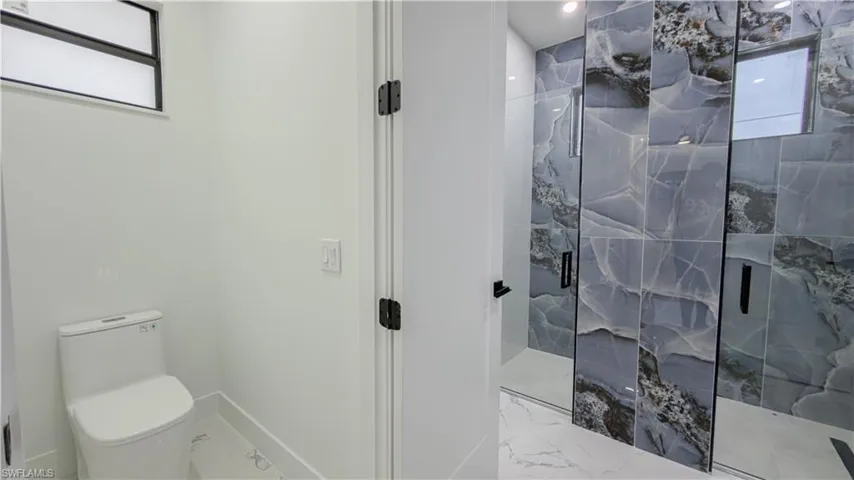 Bathroom featuring a marble finish shower and marble look tiles