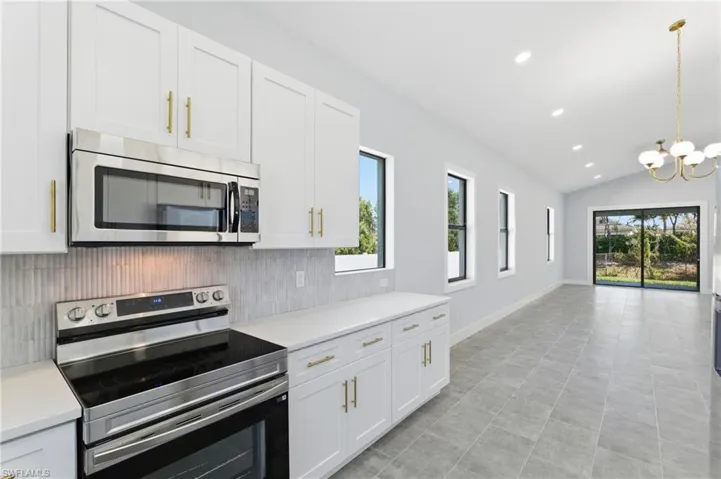 Kitchen featuring appliances with stainless steel finishes, recessed lighting, vaulted ceiling, white cabinets, and pendant lighting
