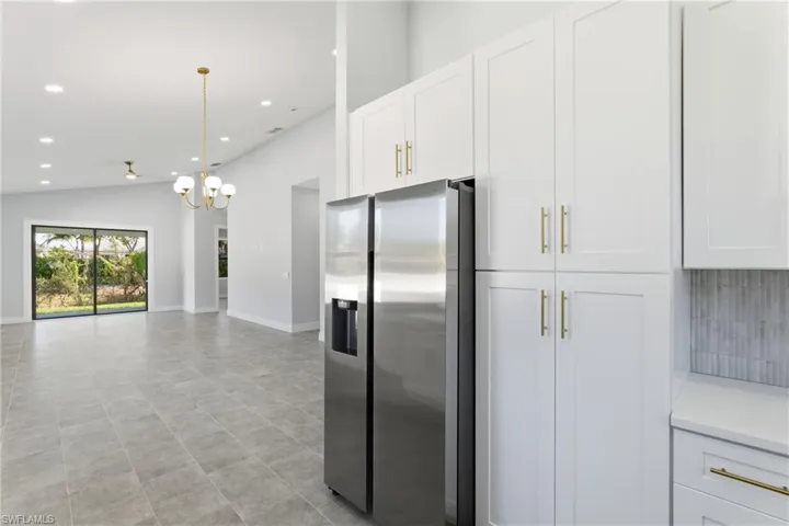 Kitchen with white cabinets, stainless steel fridge, a chandelier, recessed lighting, and hanging light fixtures