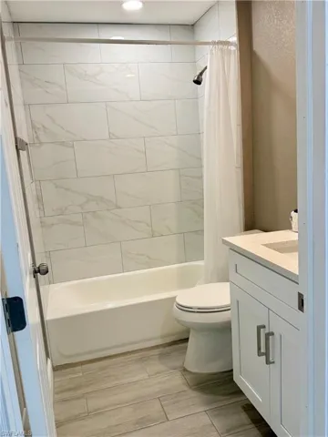 Bathroom featuring vanity, shower / tub combo with curtain, and wood finish floors