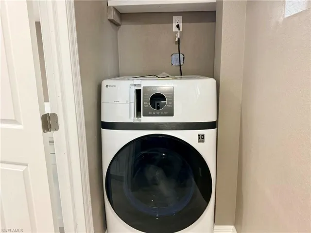 Laundry area with washer / clothes dryer and a textured wall