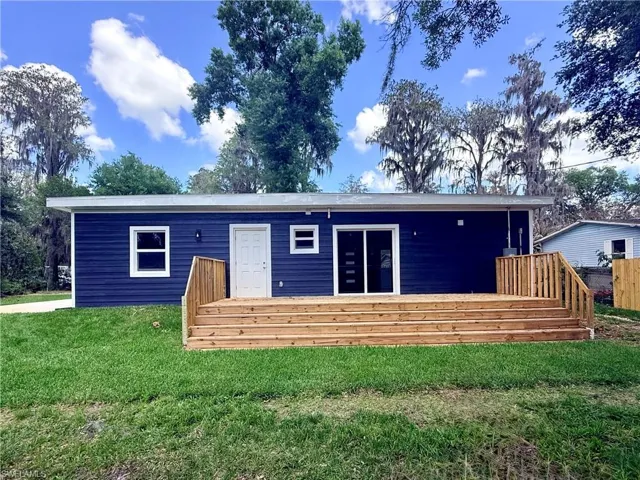Rear view of house with a deck and a lawn