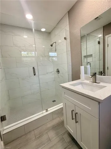 Bathroom featuring vanity, a textured wall, and a shower stall