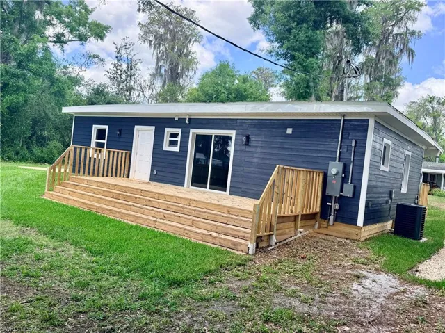 Rear view of house with a lawn and a wooden deck