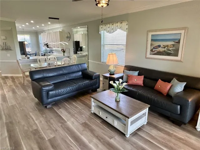 Living area with crown molding, light wood finished floors, a ceiling fan, plenty of natural light, and recessed lighting