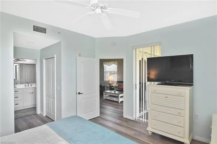 Bedroom with dark wood-style floors, ensuite bathroom, a closet, and a ceiling fan