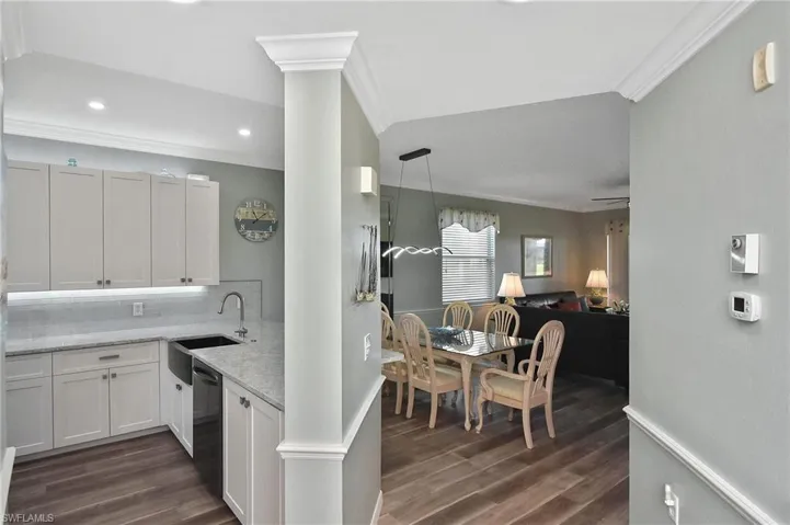 Kitchen featuring white cabinets, pendant lighting, dark wood-style floors, ornamental molding, and backsplash