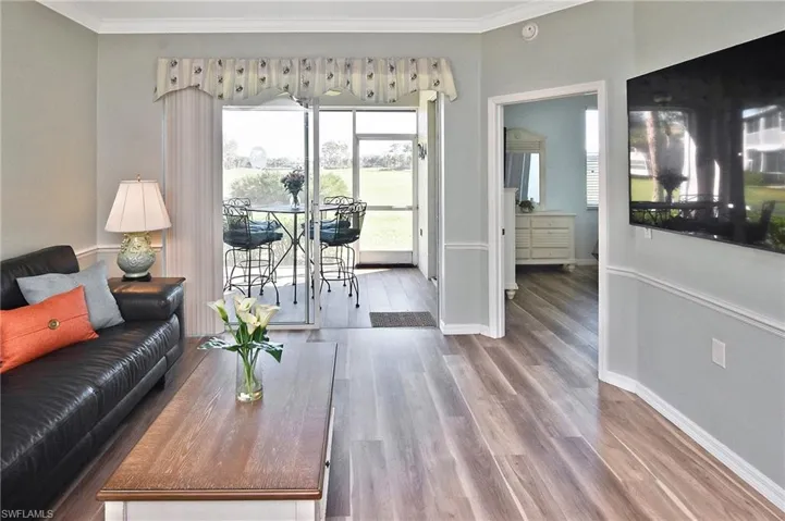 Living room with wood finished floors and ornamental molding