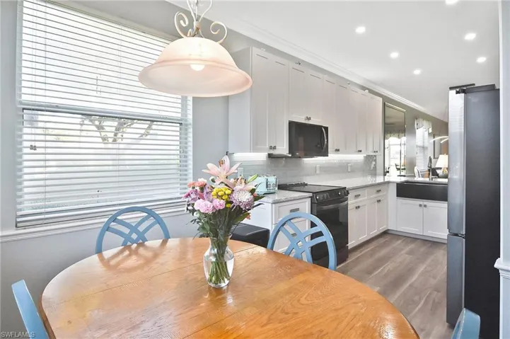 Kitchen featuring black appliances, white cabinetry, hanging light fixtures, recessed lighting, and dark wood-style floors