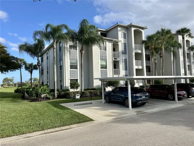 View of apartment building / complex featuring covered parking