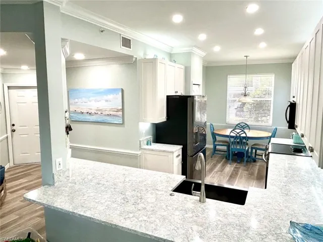 Kitchen featuring white cabinetry, a peninsula, recessed lighting, ornamental molding, and pendant lighting
