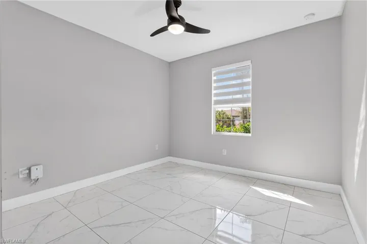 Empty room with light marble finish floors and a ceiling fan