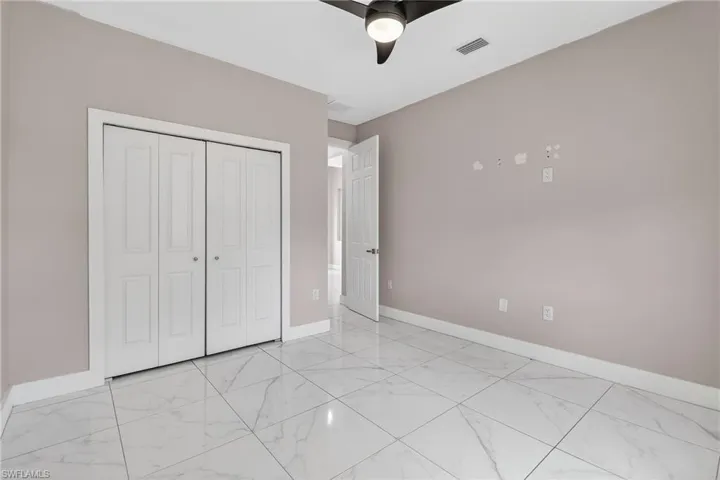 Unfurnished bedroom featuring a closet, ceiling fan, and light marble finish flooring