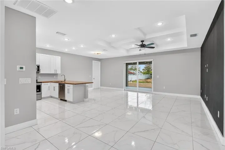 Kitchen with a peninsula, coffered ceiling, white cabinets, recessed lighting, and open floor plan
