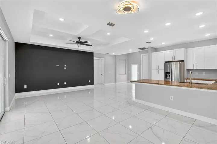 Kitchen featuring white cabinetry, a peninsula, recessed lighting, dark stone counters, and stainless steel fridge with ice dispenser