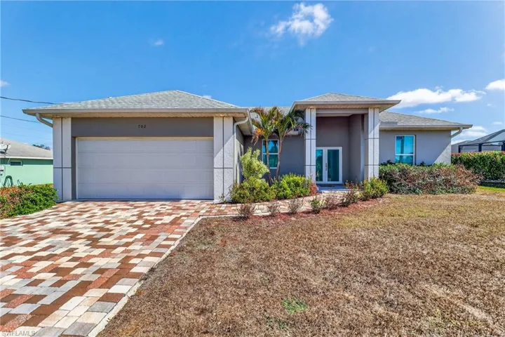 View of front of home with french doors, stucco siding, driveway, a garage, and a shingled roof