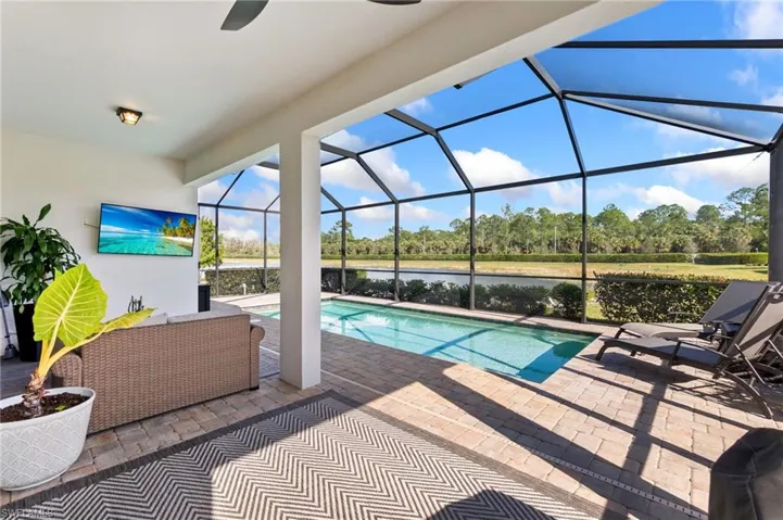 Outdoor pool featuring a patio, a sunroom, a lanai, and view of wooded area