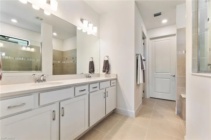 Full bathroom featuring a walk in shower, double vanity, light tile patterned floors, and recessed lighting