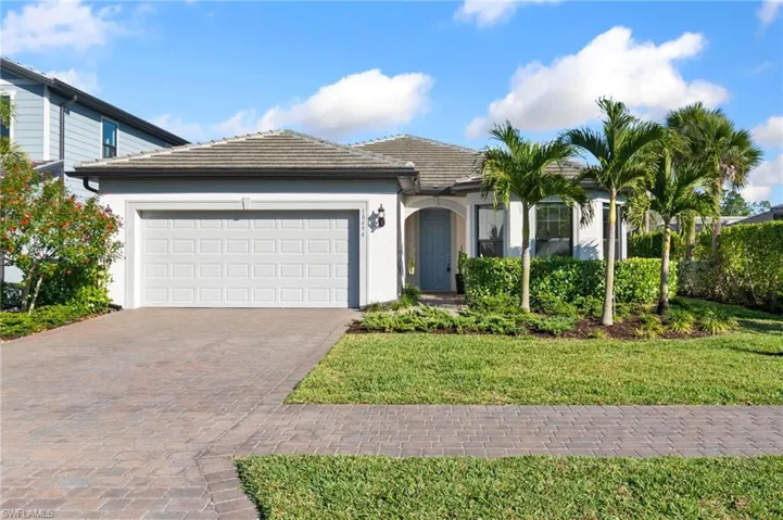 Ranch-style house featuring decorative driveway, a garage, stucco siding, a tiled roof, and a front yard