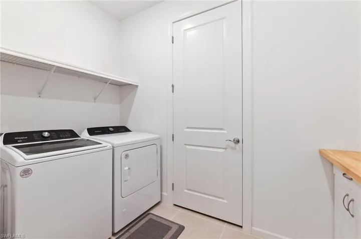 Washroom featuring light tile patterned floors and washing machine and clothes dryer