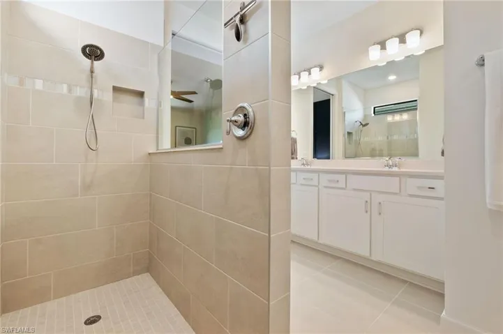 Full bath with a walk in shower, vanity, and light tile patterned floors