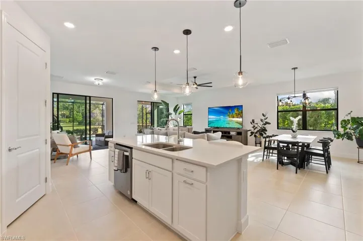 Kitchen with a ceiling fan, white cabinetry, hanging light fixtures, recessed lighting, and a kitchen island with sink