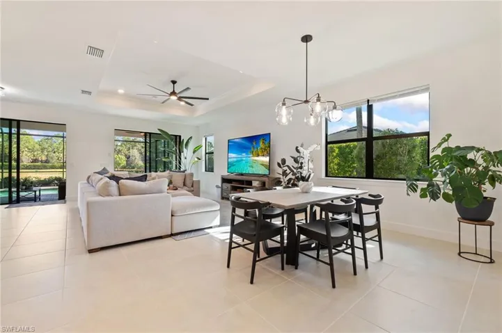 Dining space featuring a raised ceiling, a ceiling fan, a chandelier, and light tile patterned flooring