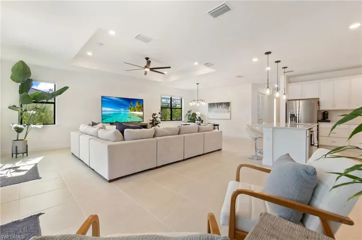 Living area featuring a chandelier, a tray ceiling, recessed lighting, a ceiling fan, and light tile patterned floors