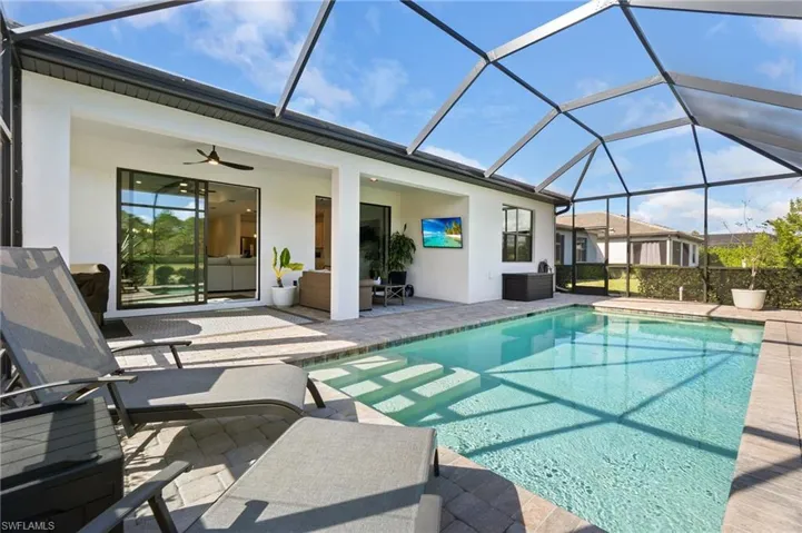 Swimming pool featuring glass enclosure, a sunroom, and a patio area