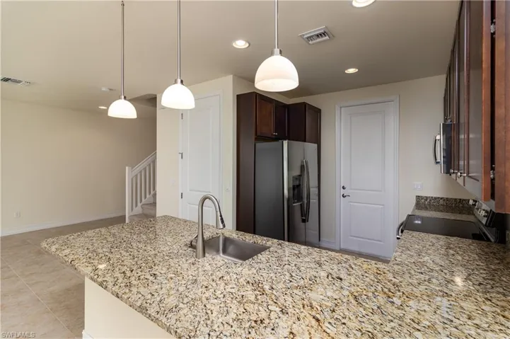 Kitchen featuring stainless steel fridge, range, decorative light fixtures, sink, and light tile flooring