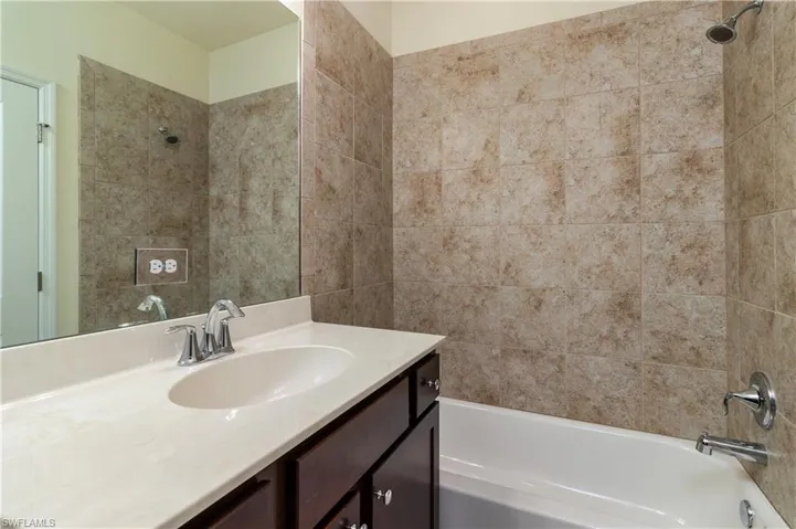 Bathroom featuring tiled shower / bath and vanity