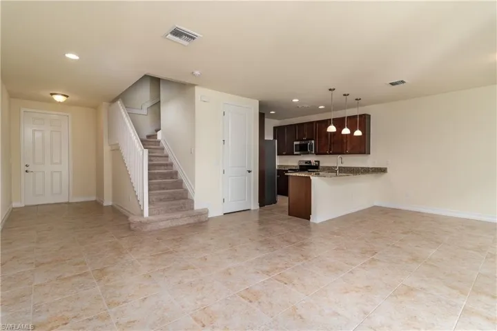 Kitchen featuring hanging light fixtures, kitchen peninsula, dark brown cabinetry, and light tile floors