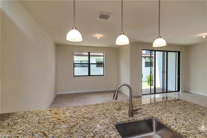 Kitchen featuring light stone countertops, light tile floors, and pendant lighting
