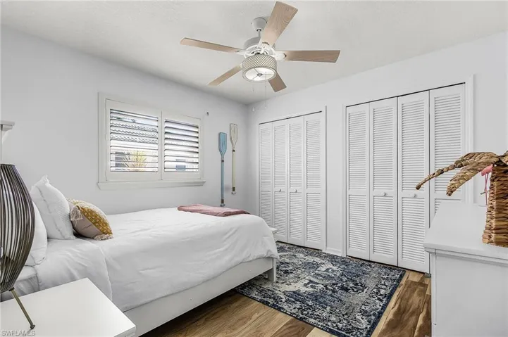 Bedroom with two closets, wood finished floors, ceiling fan, and a textured ceiling