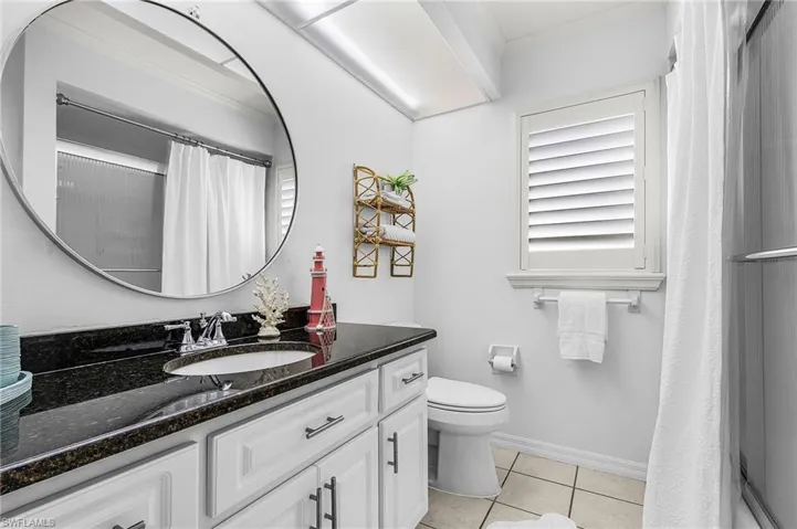 Bathroom with vanity, a shower with shower curtain, light tile patterned floors, and crown molding